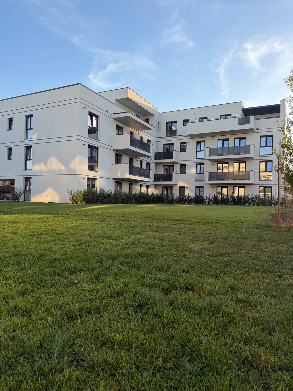 Corp A finalizat – fațada clădirii cu balcoane, văzută peste spațiul verde amenajat